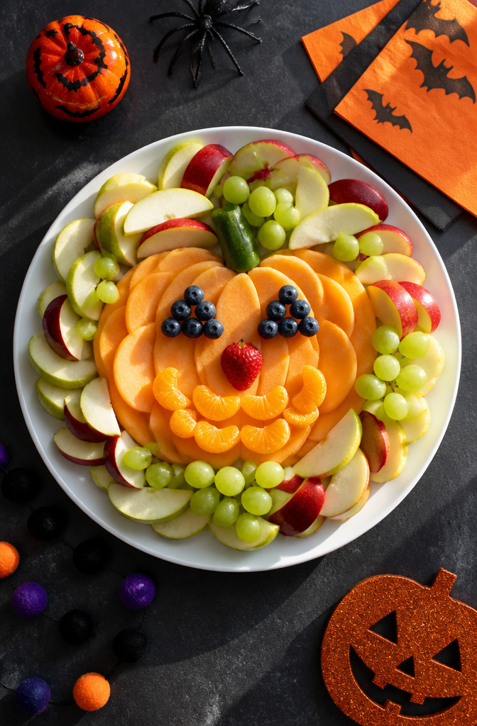 A platter of assorted fruits arranged to look like a pumpkin.