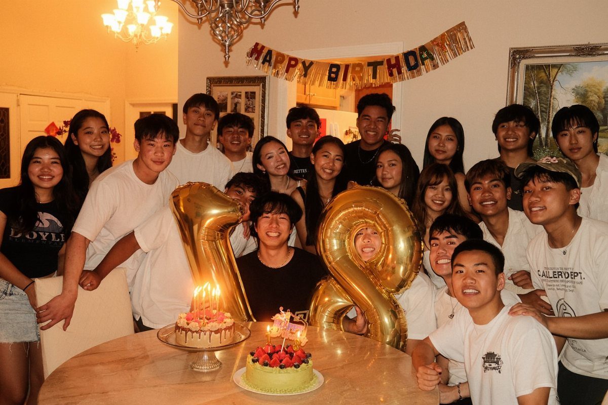 Group of young adults celebrating a birthday with cakes and gold number 18 balloons.