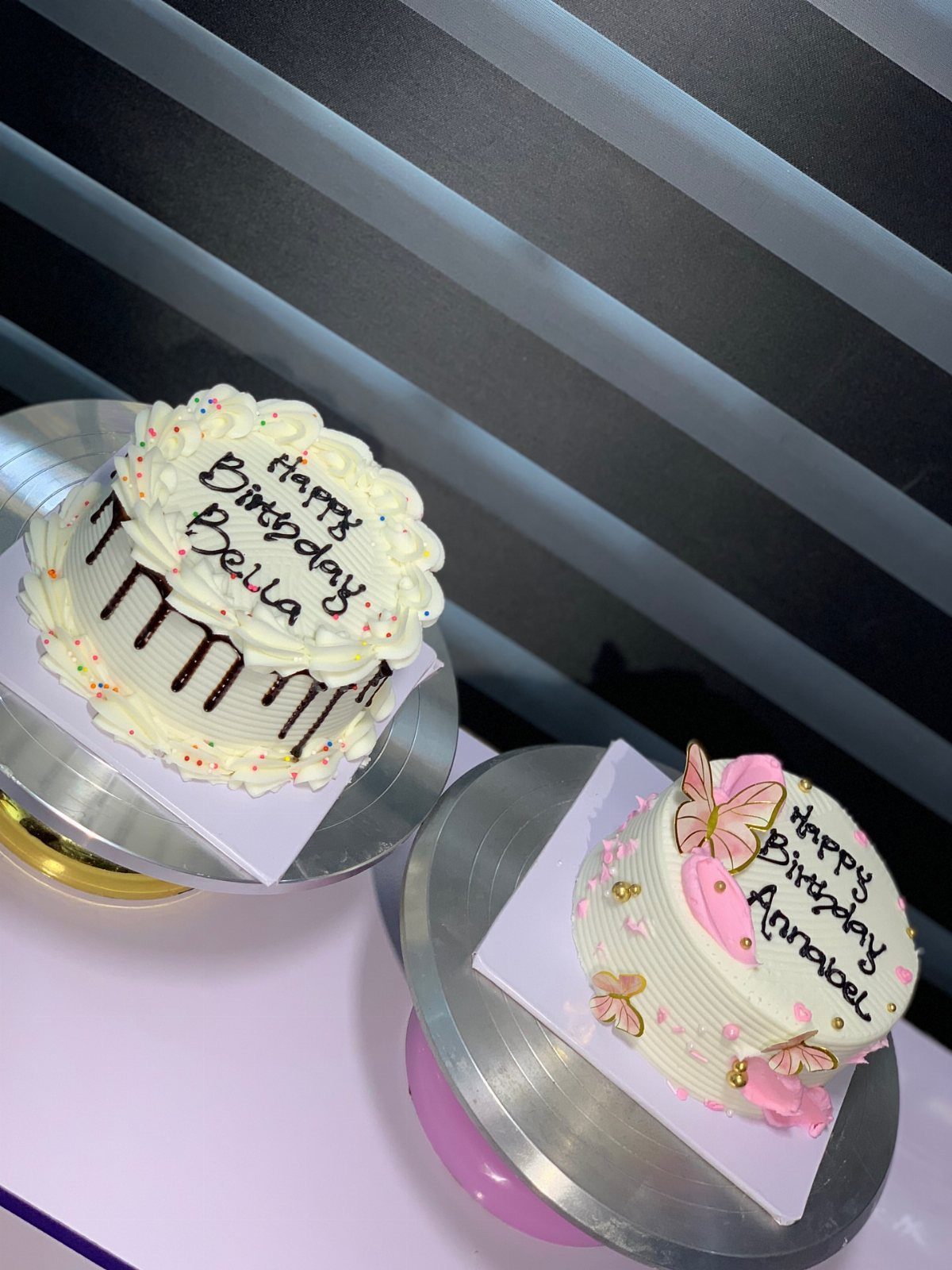 Two small white birthday cakes with chocolate drip and pink butterfly decorations.