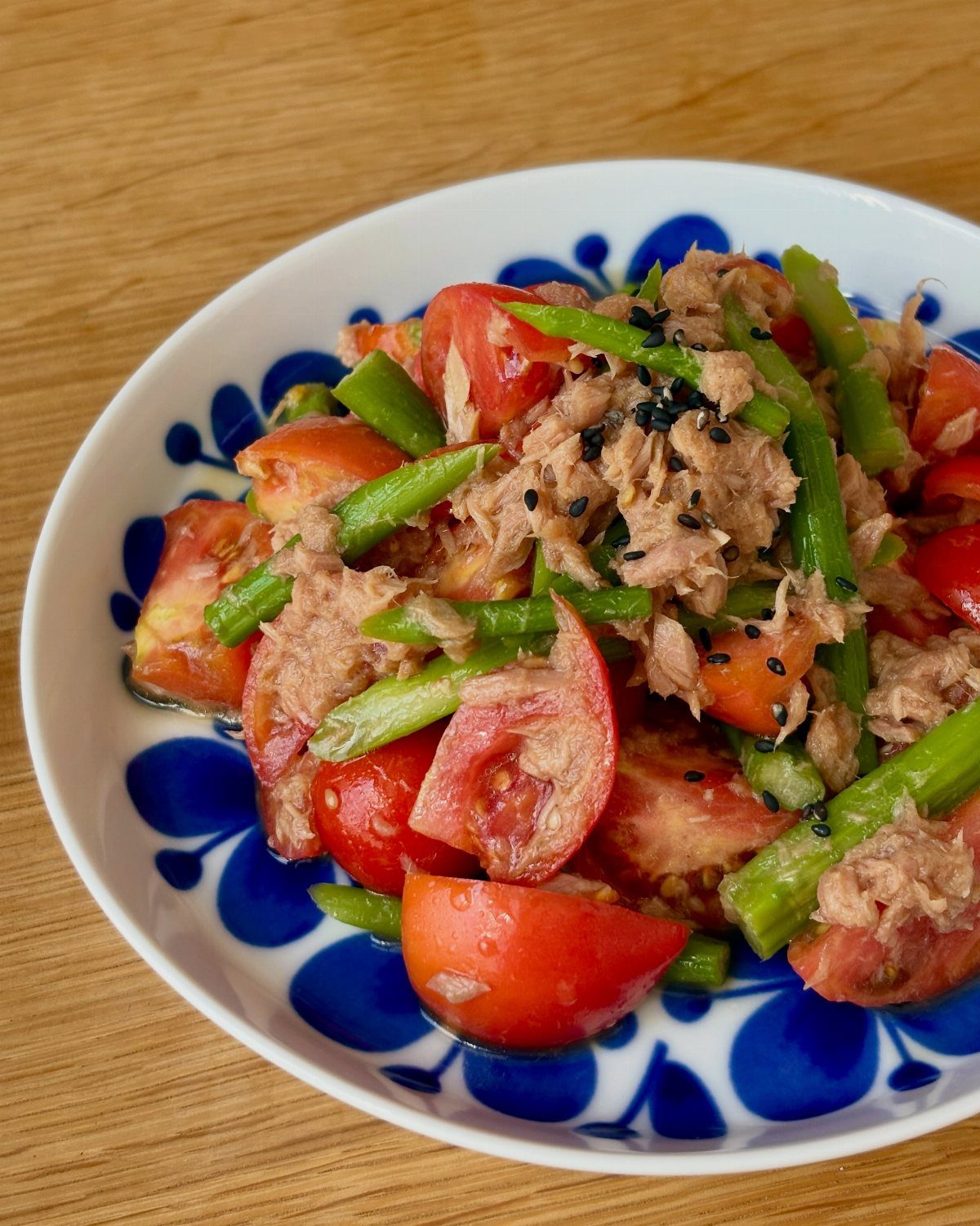 Tuna salad with cherry tomatoes and green beans in a blue patterned bowl.