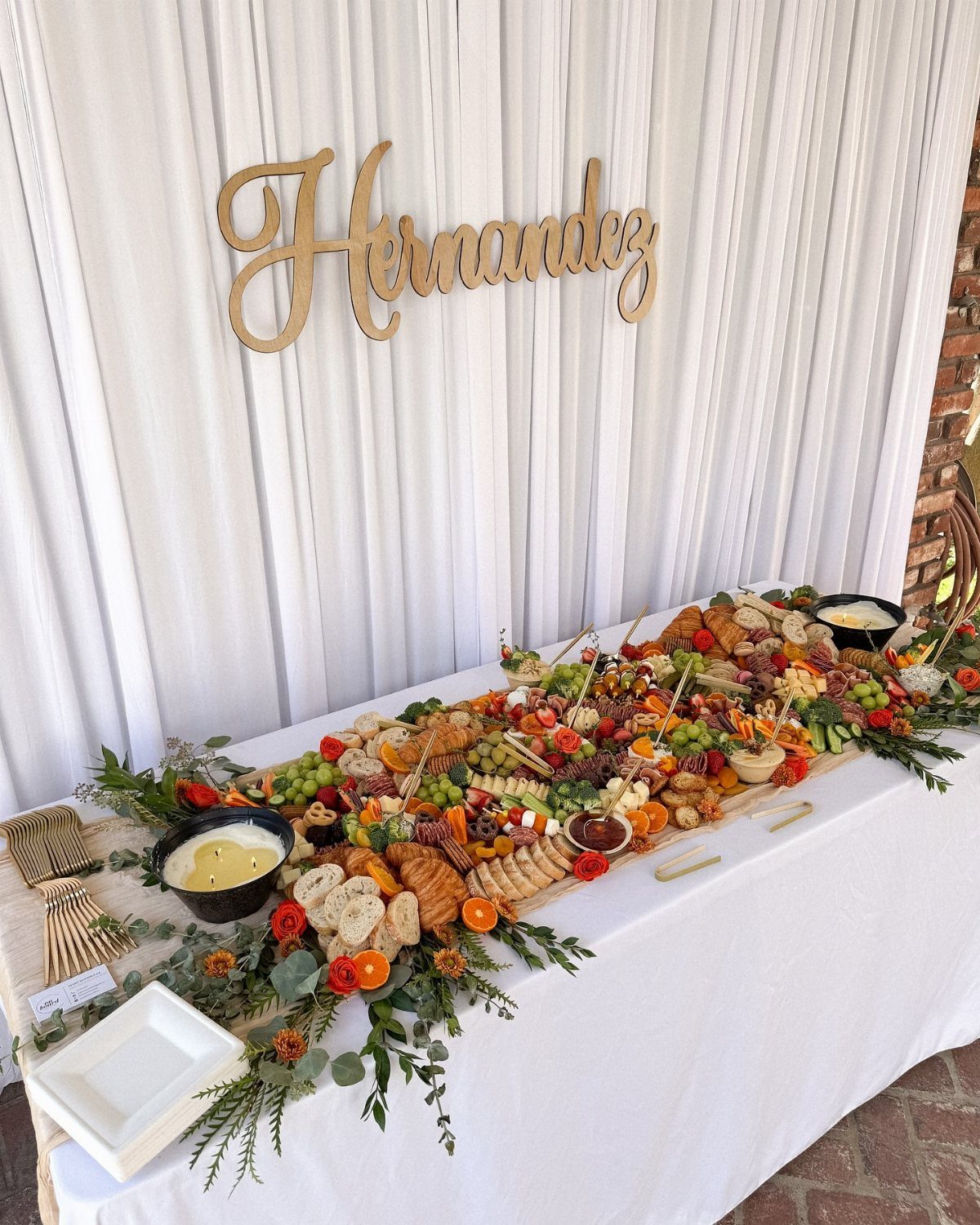 Wedding grazing table with meats and cheeses under a gold Hernandez name sign.