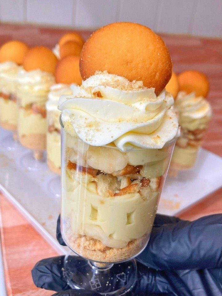 Banana pudding parfait with layers of cream, bananas, and wafers in a glass.