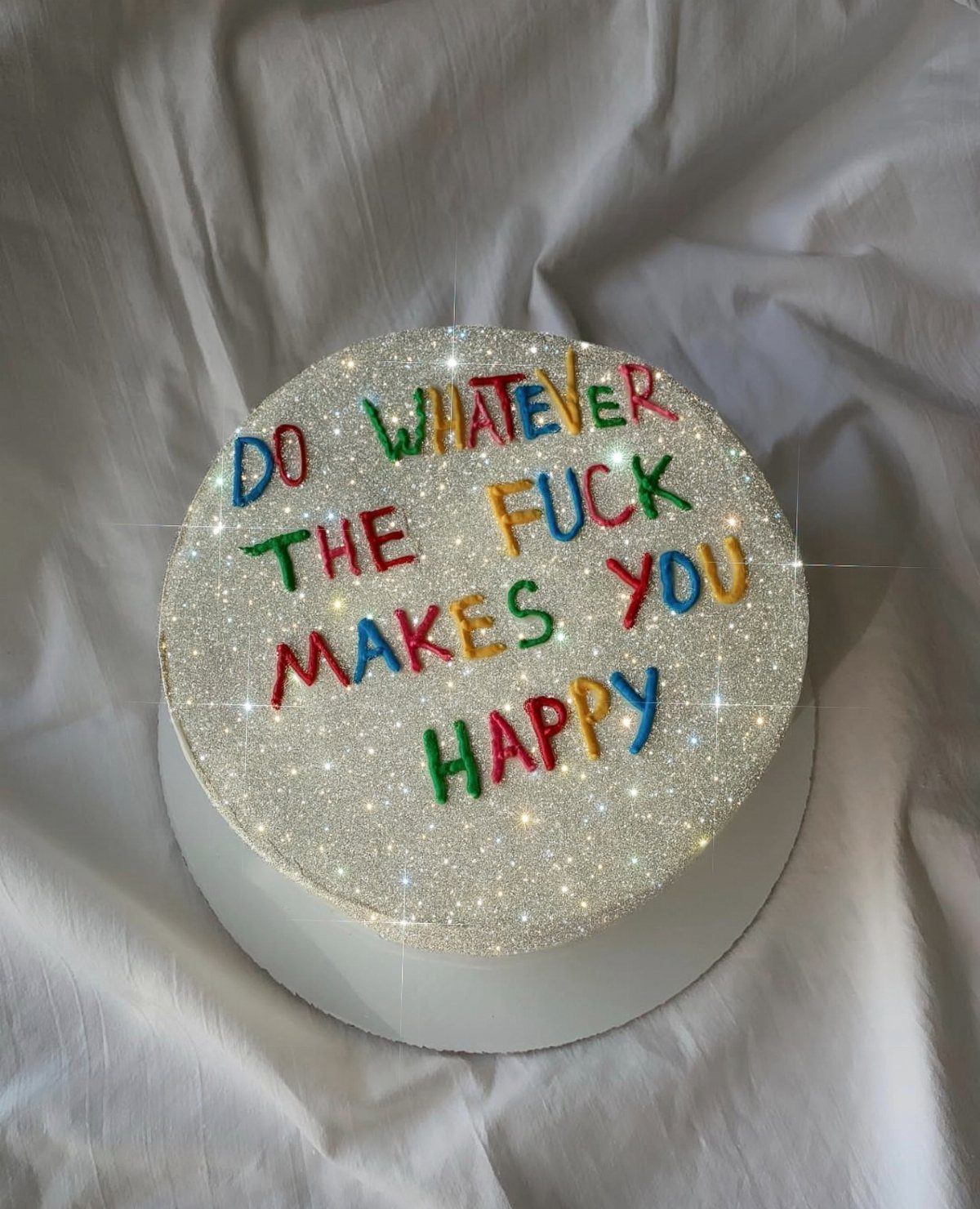 Silver glitter cake with colorful lettering saying do whatever the fuck makes you happy