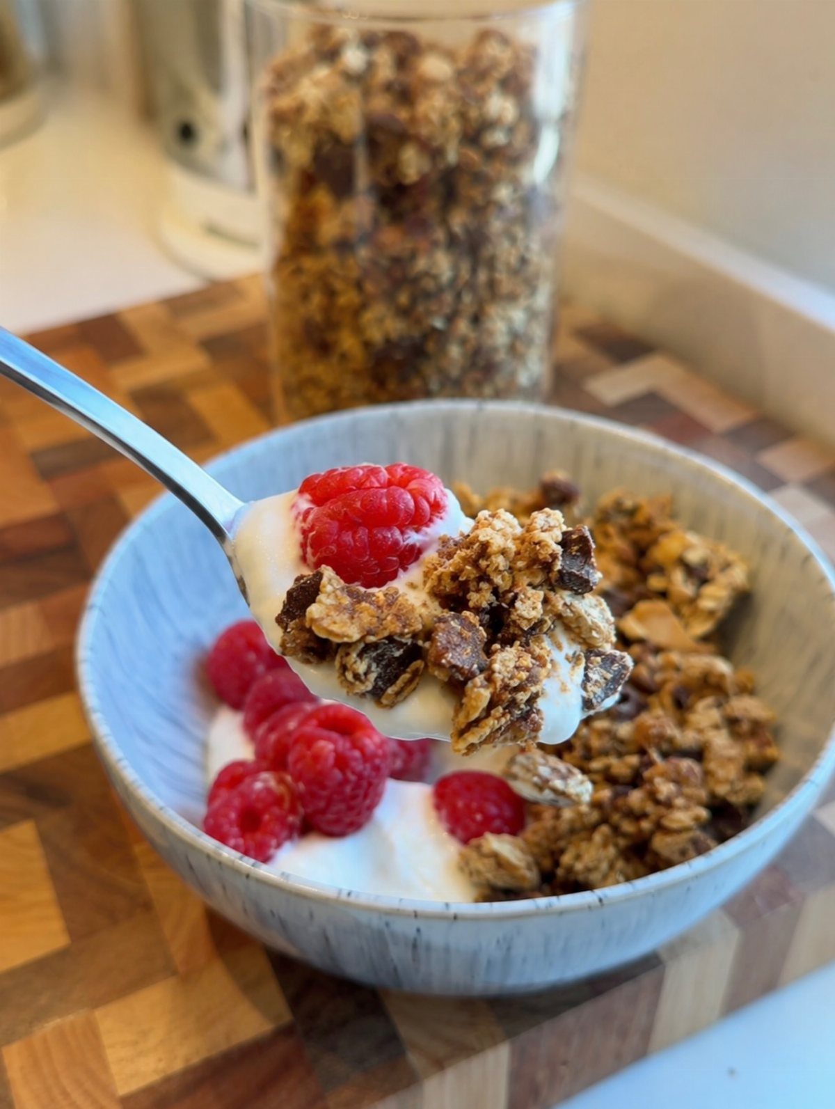 Yogurt bowl with fresh red raspberries and crunchy granola on a wooden board